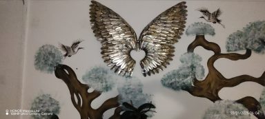 Metallic angel wings with birds and stylised trees in a decorative wall art design.